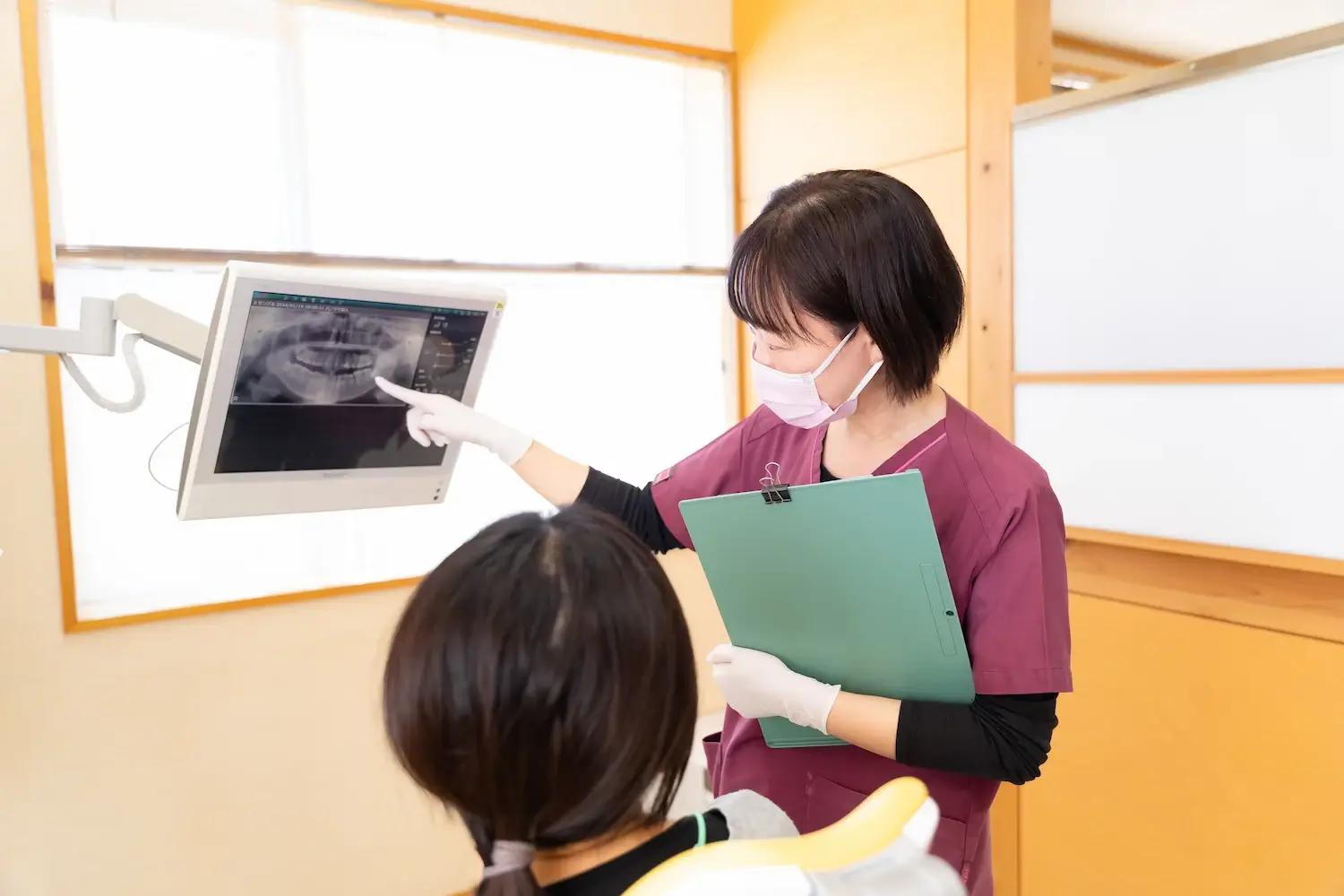 モニターを使って説明する知立市シン歯科クリニックのスタッフと患者さん