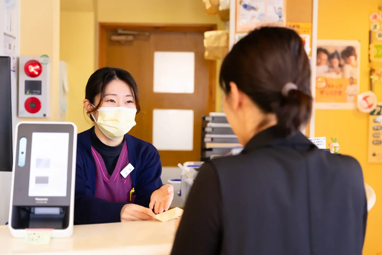 患者さんに診察券を渡す知立市シン歯科クリニックの受付スタッフ